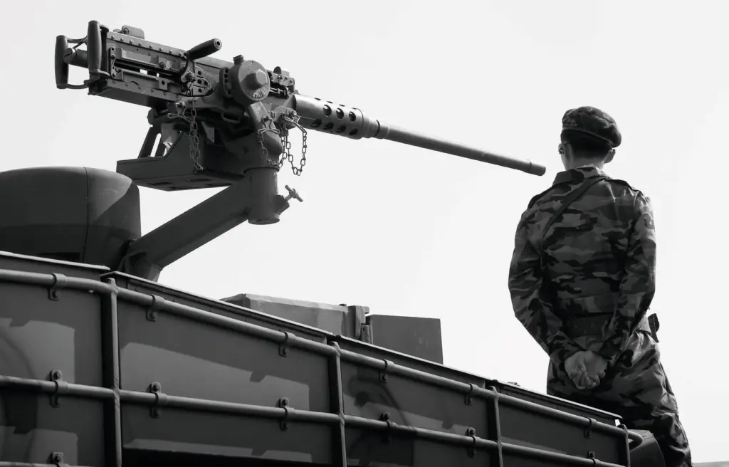 Ein Soldat in Uniform steht auf einem Panzer, hinter ihm ist ein Maschinengewehr zu sehen. Credit: Noh Suntag